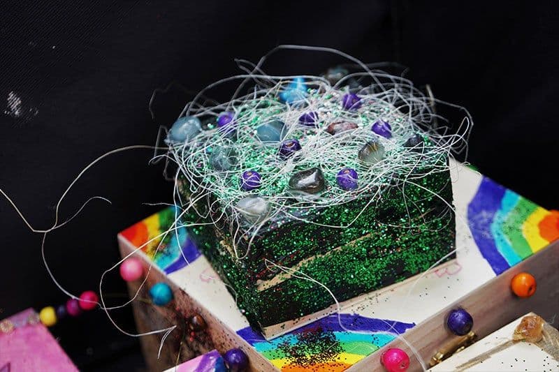 Eine Holzkiste ist mit Glitzer und Perlen beklebt.