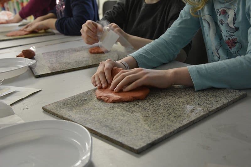 Ein Kind knetet braunen Ton.