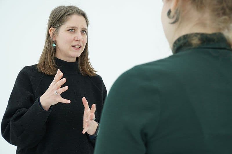 Zwei Personen stehen sich gegenüber. Die eine Person erklärt etwas in Gebärdensprache.