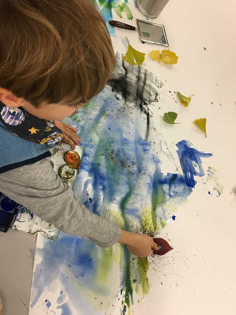 Ein Kind malt mit Wasserfarben.